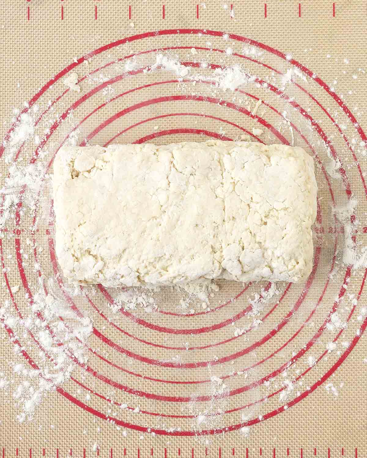 Dough shaped into a rectangle on a floured pastry mat.