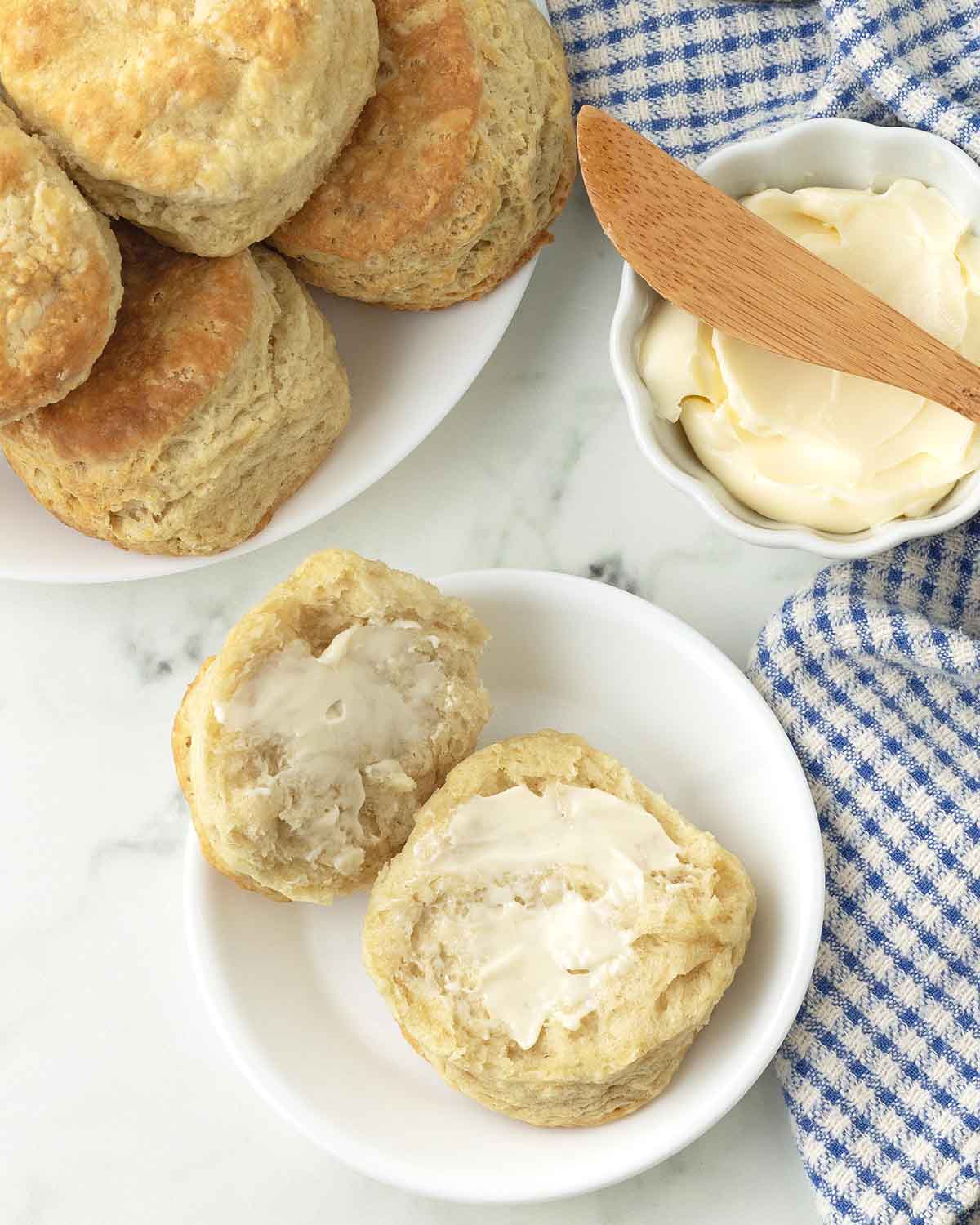 A vegan biscuit split in two spread with butter on each side.