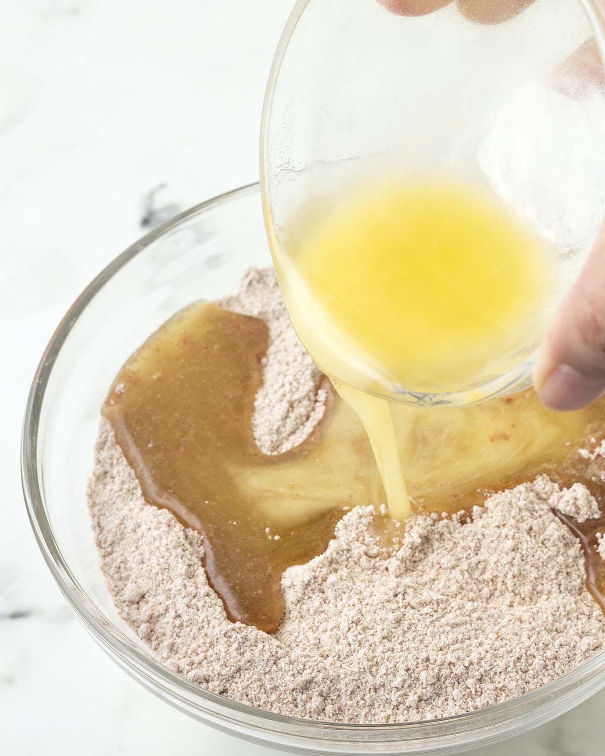 Melted butter being poured into a bowl of dry ingredients.