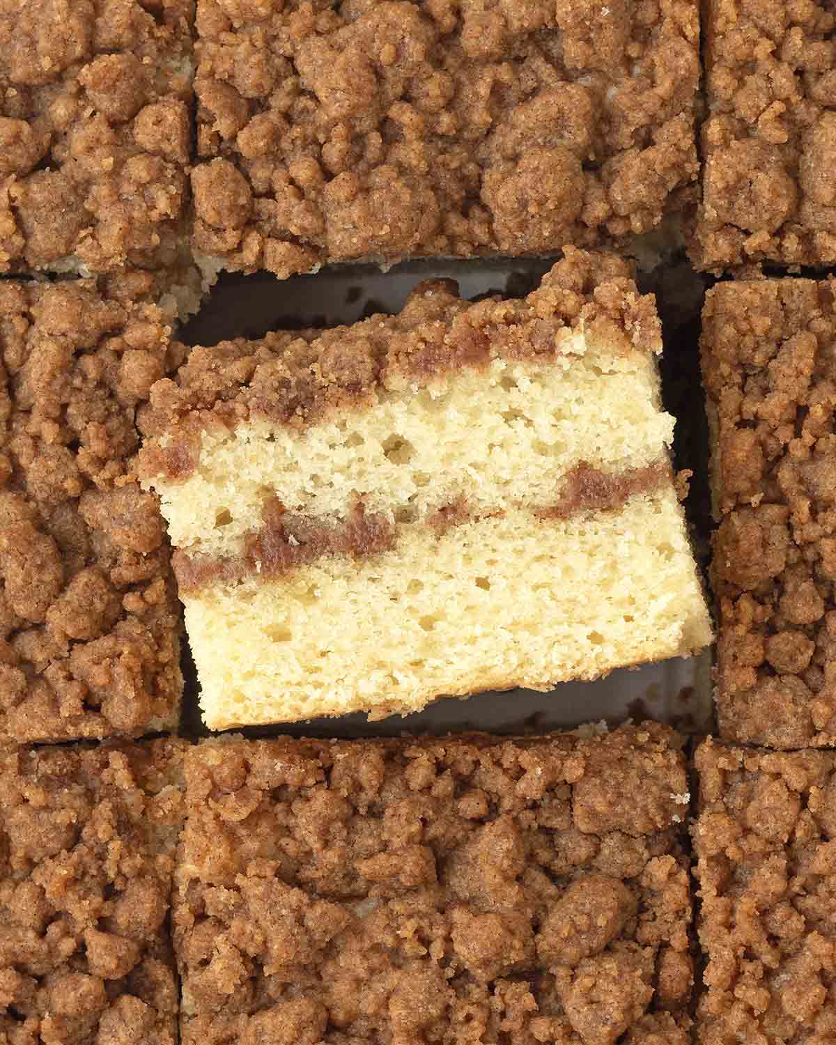 An overhead image of sliced coffee cake, the square in the middle is on its side to show the fluffy texture.