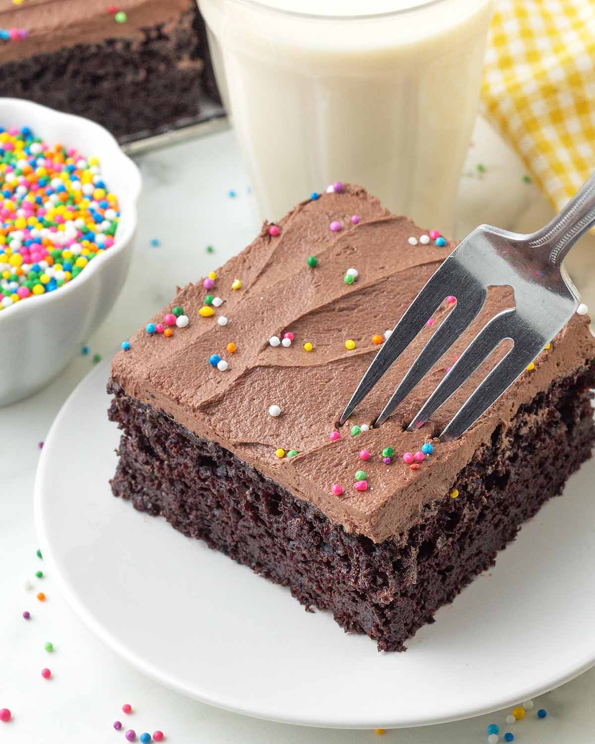 A fork digging into a square of frosted vegan chocolate sheet cake.