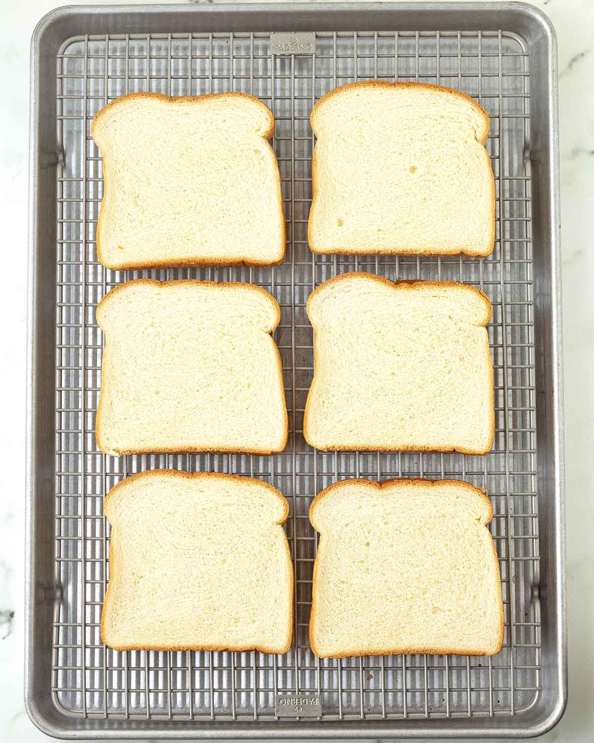 Six slices of brioche bread on a metal rack.