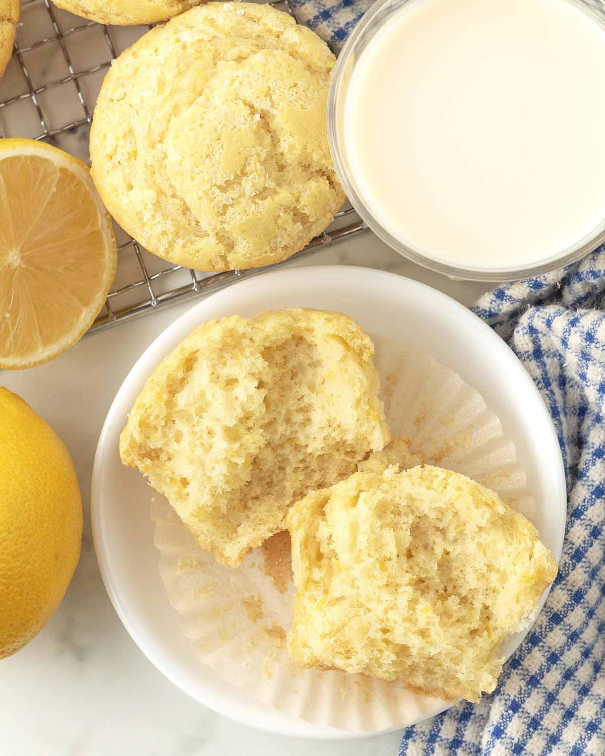 A lemon muffin on a small plate, the muffin has been split in half to show the fluffy interior.