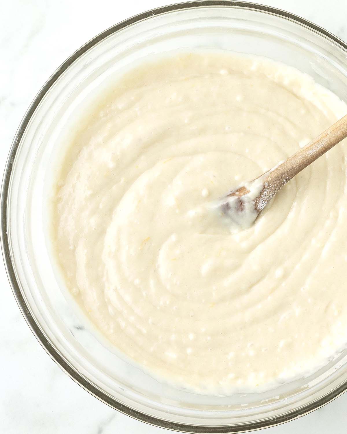 Mixed muffin batter for vegan lemon muffins in a glass bowl.