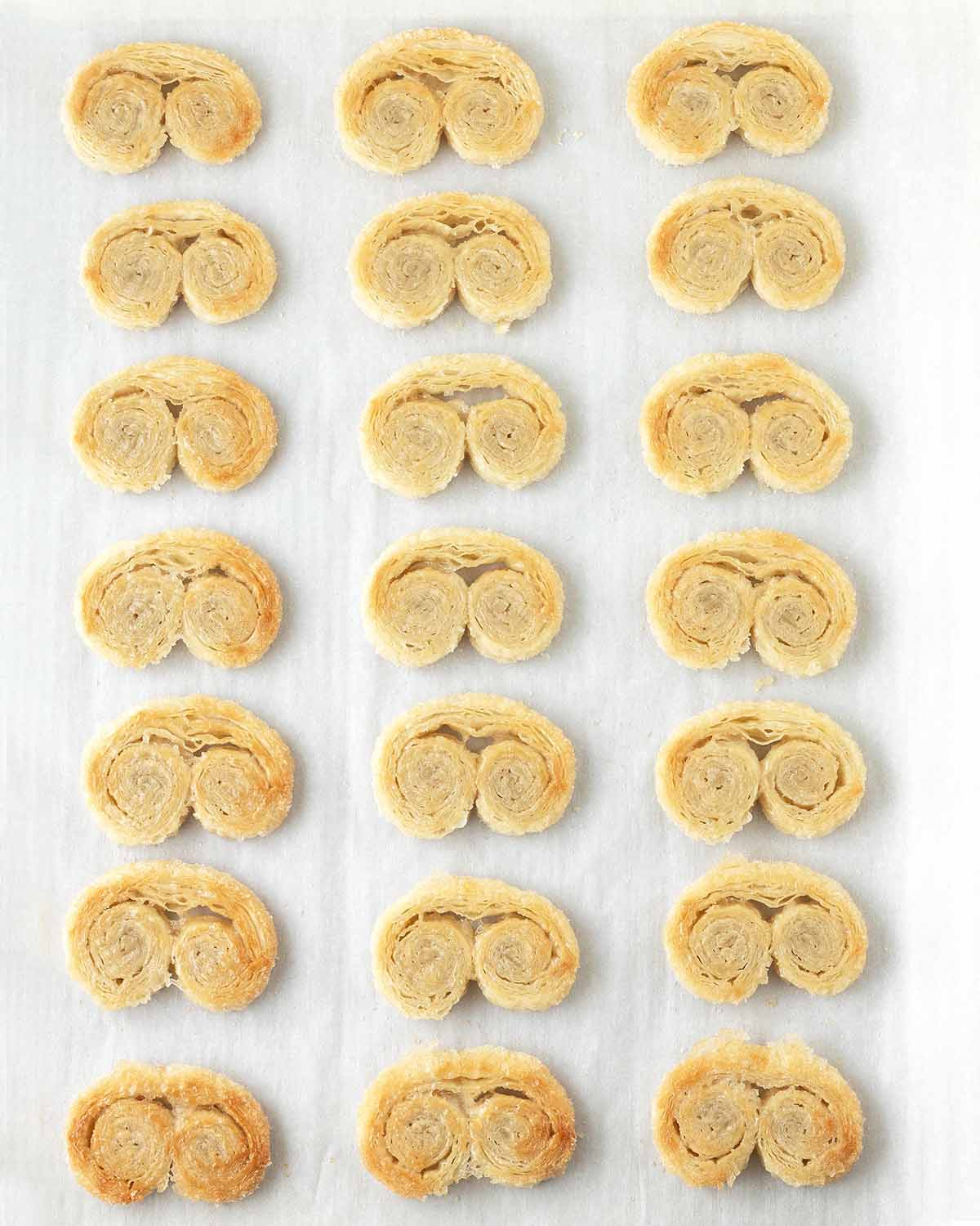 Flipped, half baked palmiers on a parchment lined baking sheet.