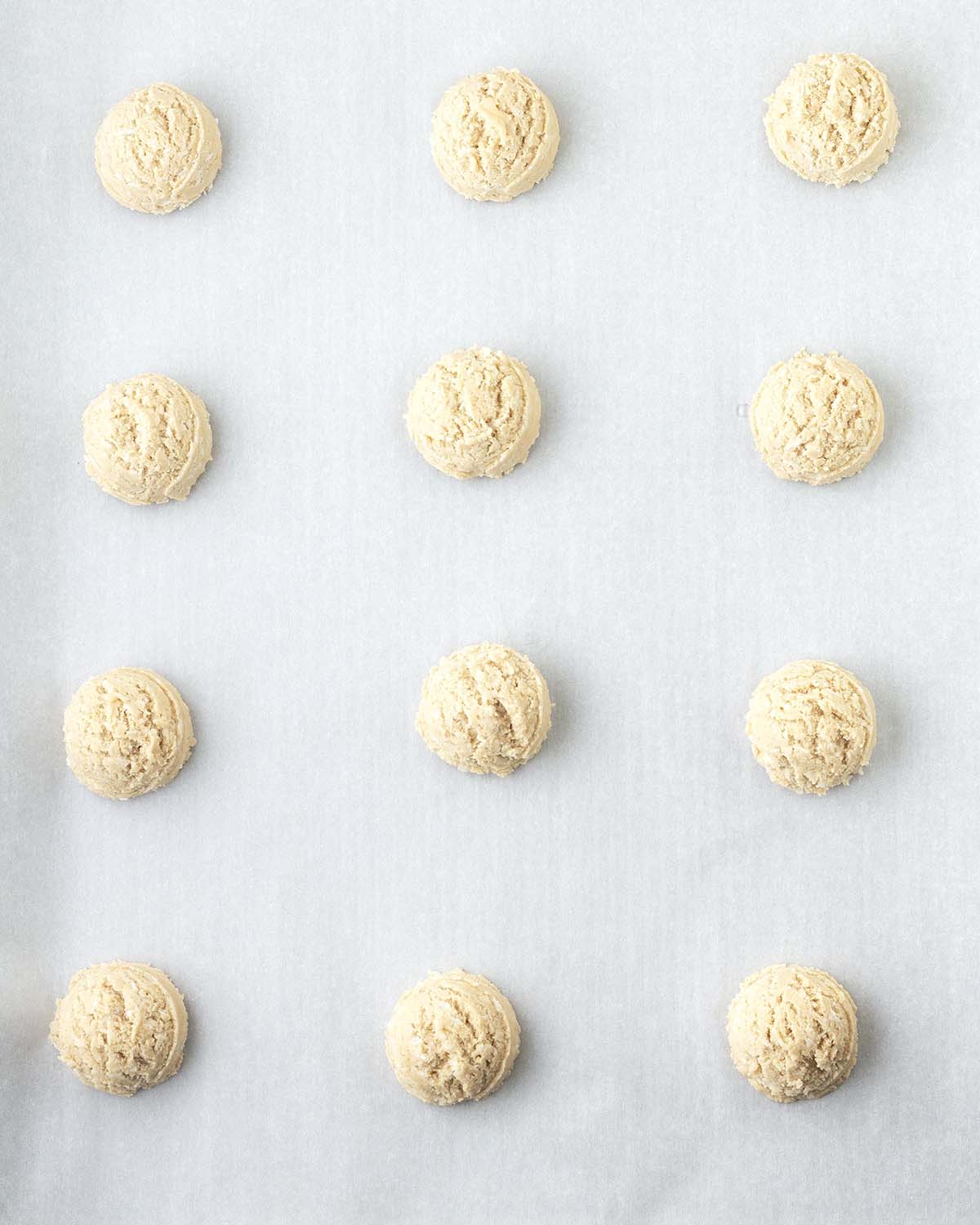 Raw coconut cookie dough balls on a cookie sheet.