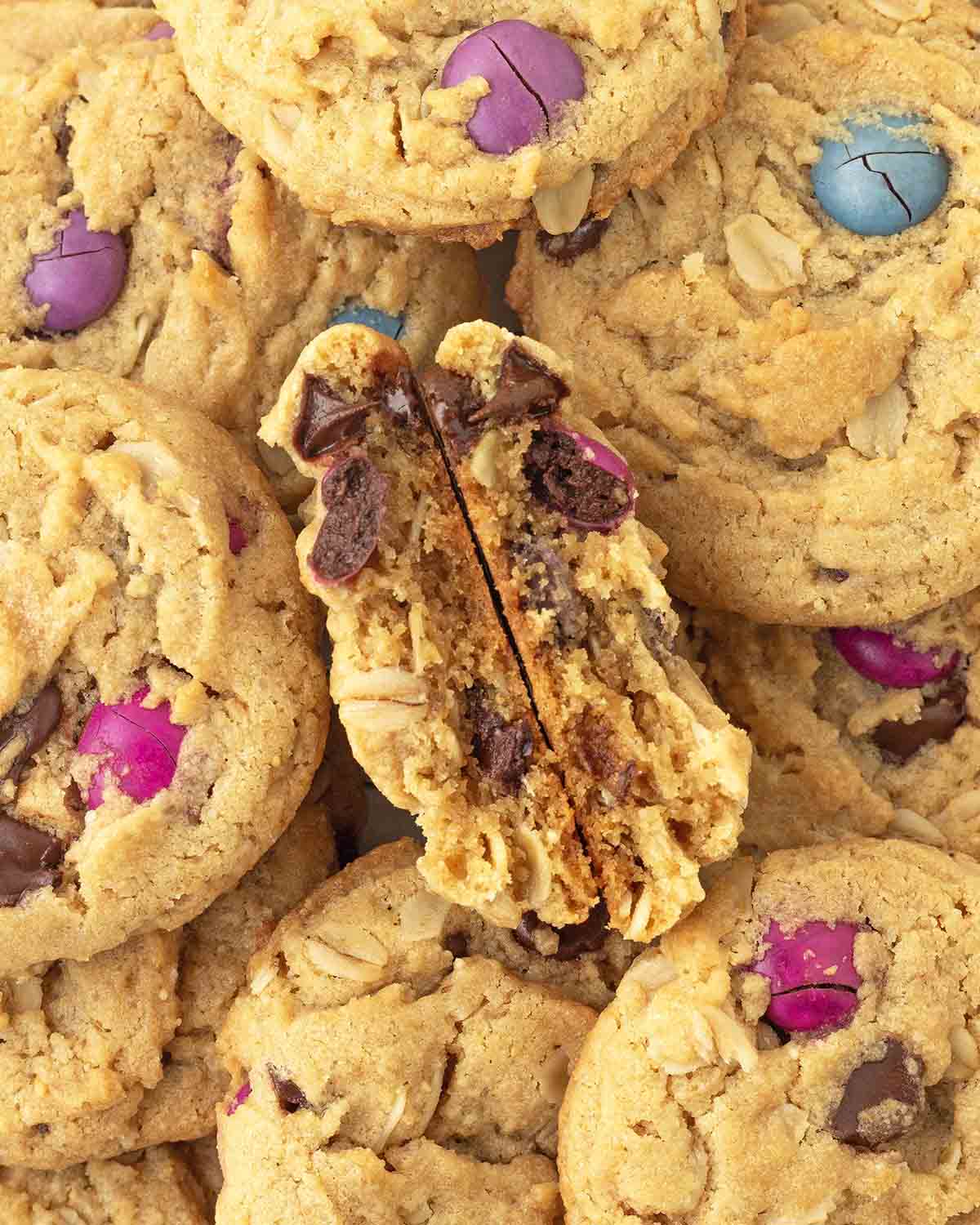 An overhead image of monster cookies, one cookie is split in half to show the soft inside.