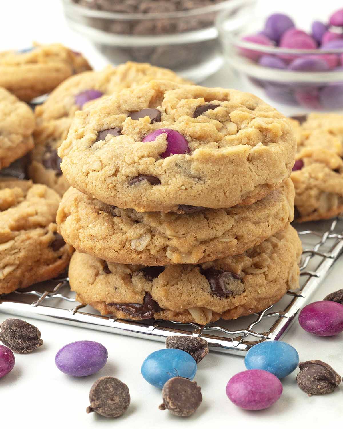 A stack of three vegan monster cookies sitting on a metal rack.