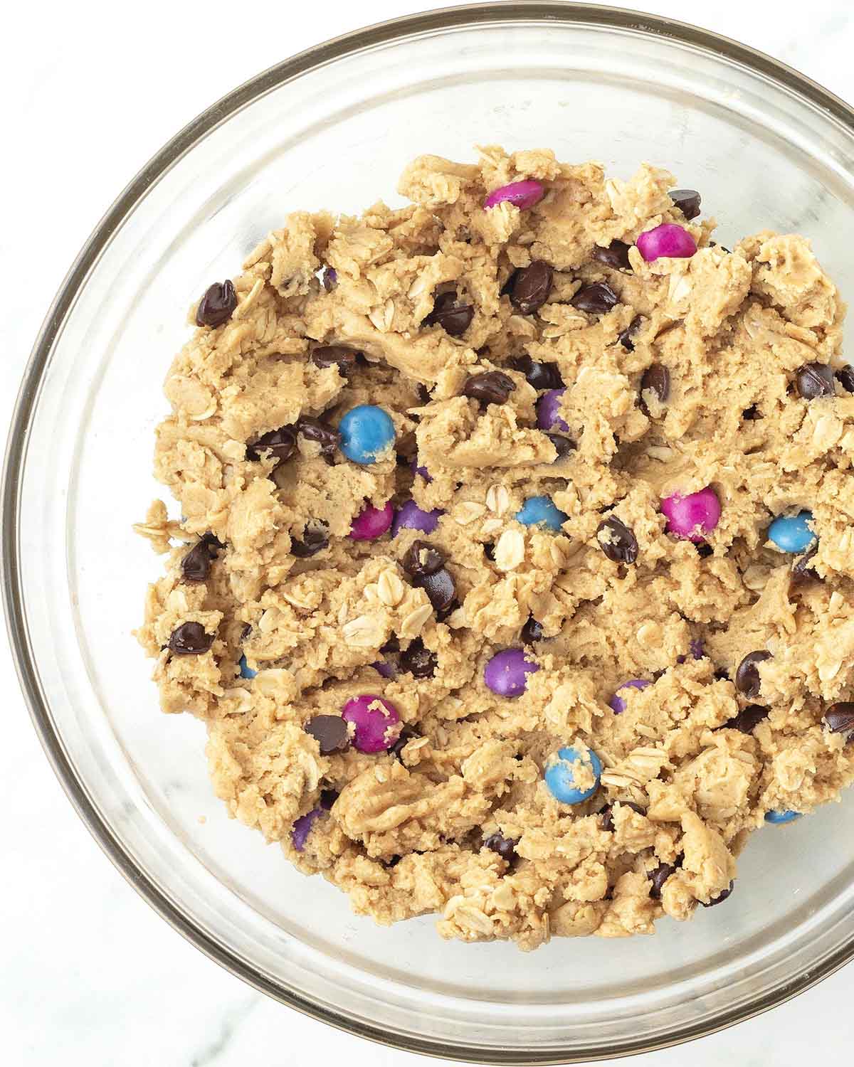 Monster cookie dough in a glass bowl.