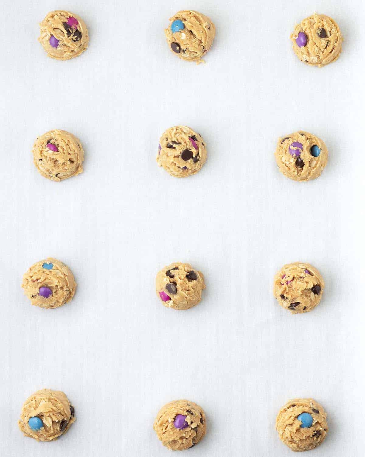 Raw monster cookie dough balls on a cookie sheet.