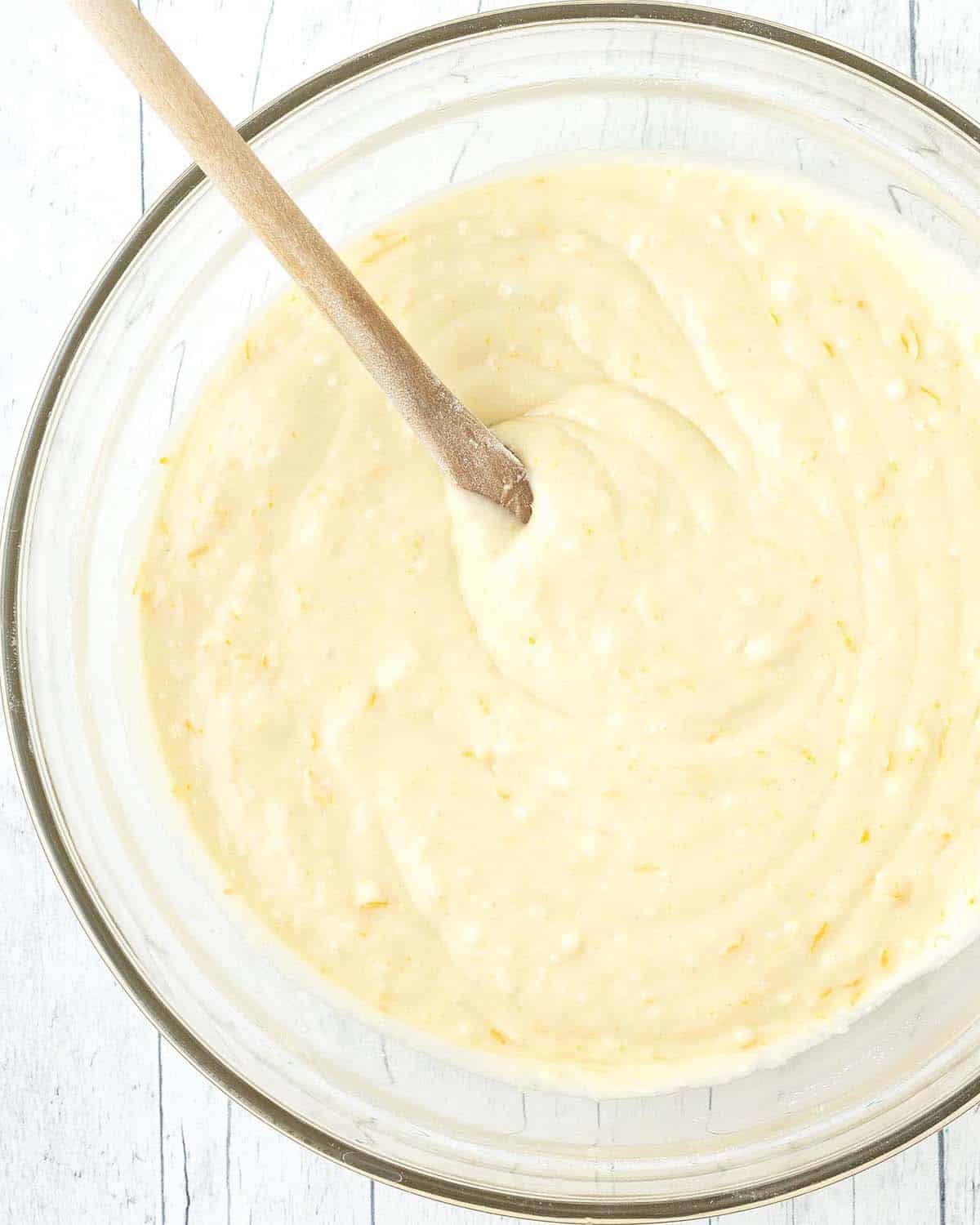 Mixed muffin batter for vegan orange muffins in a glass bowl.