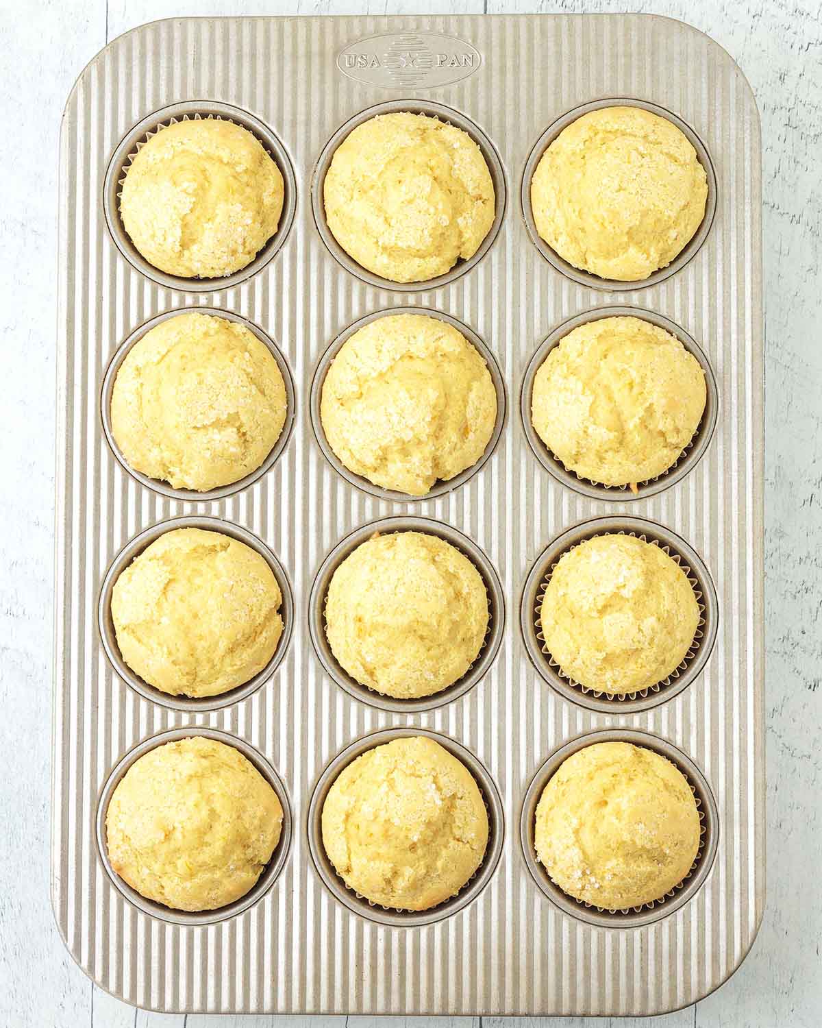 Freshly baked orange muffins in a muffin pan.