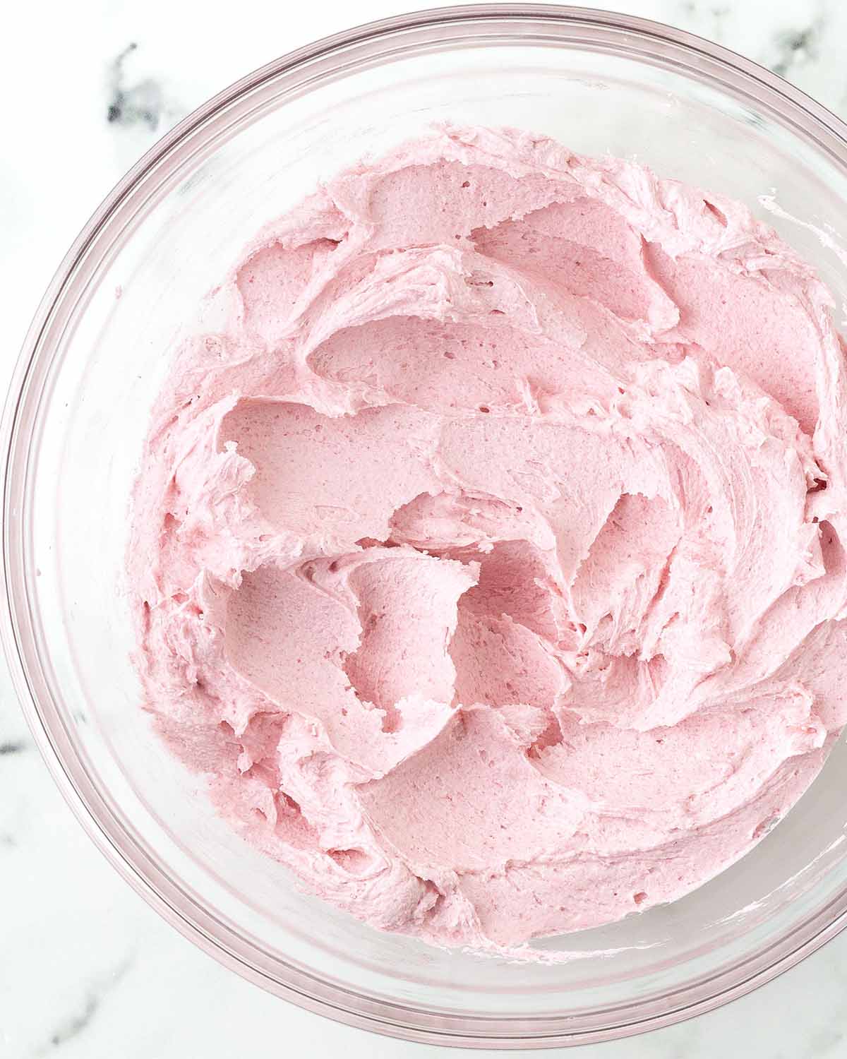 Raspberry frosting made with freeze-dried raspberries in a glass bowl.