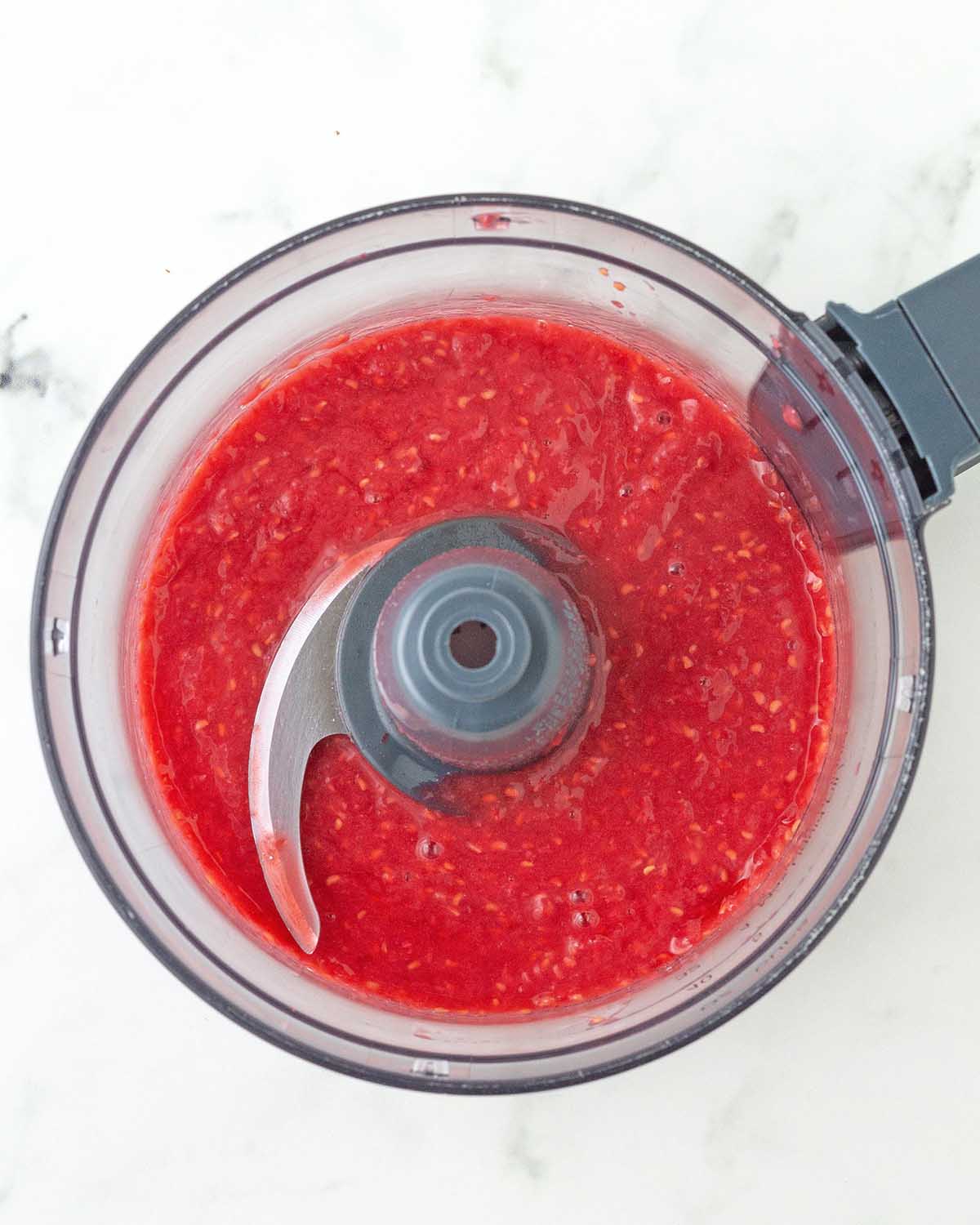 Pureed fresh raspberries in a food processor.