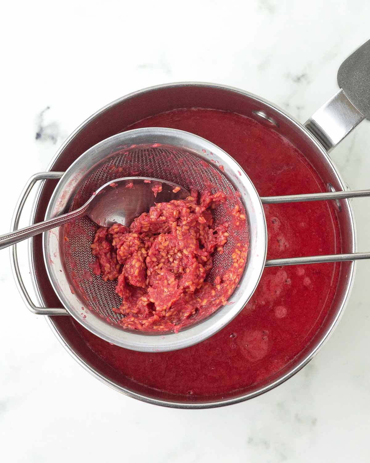 The leftover seeds and pulp in a sieve from pureed fresh raspberries.