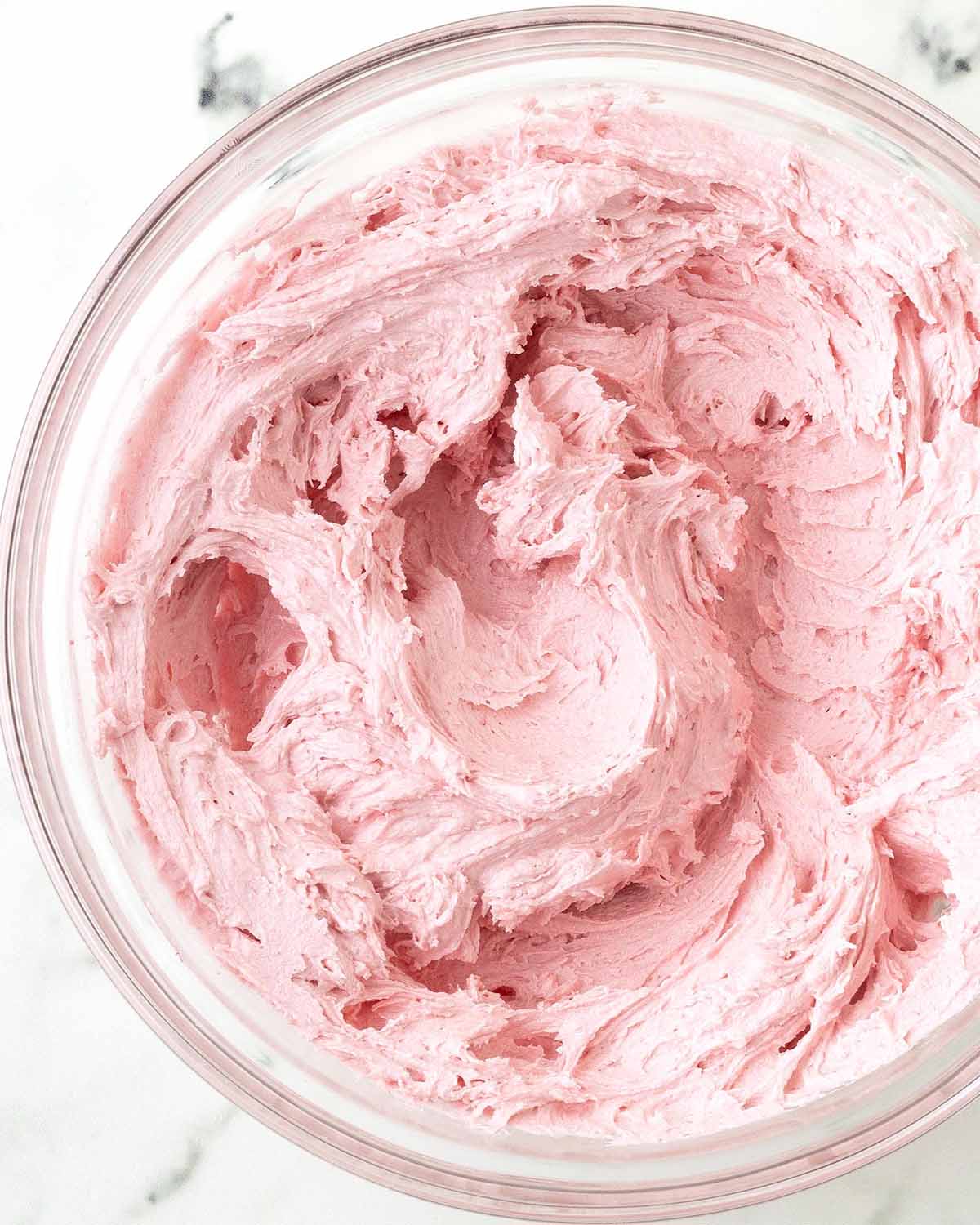 Raspberry frosting made with fresh raspberries in a glass bowl.