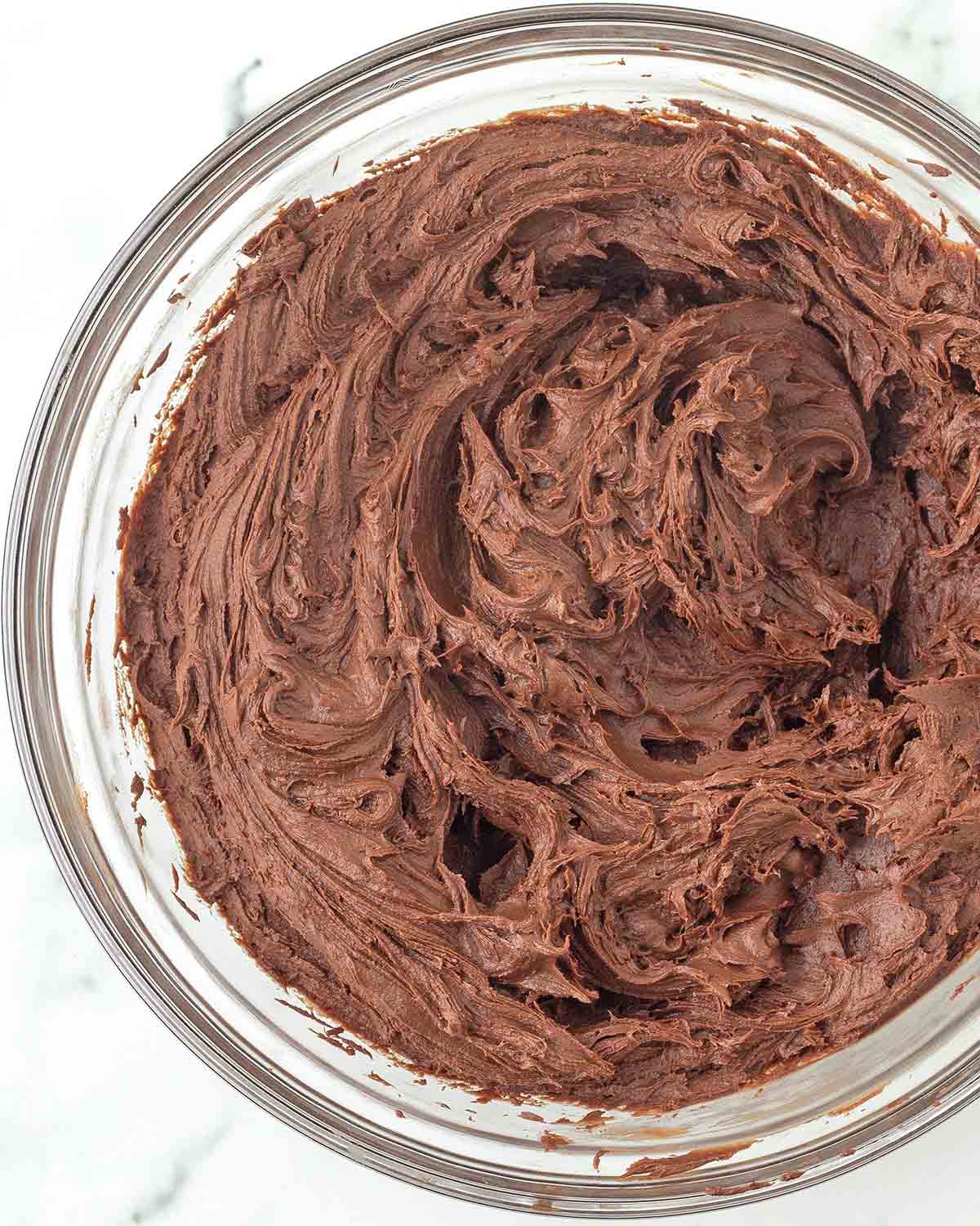 Whipped vegan chocolate ganache frosting in a glass bowl.