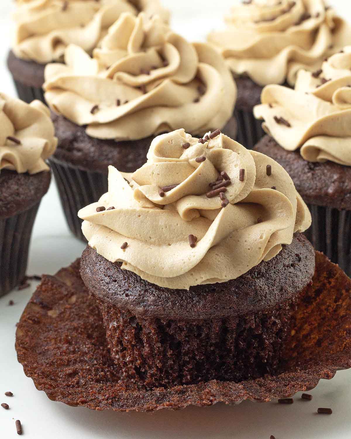 An chocolate cupcake on a plate, the cupcakes wrapper has been peeled away.