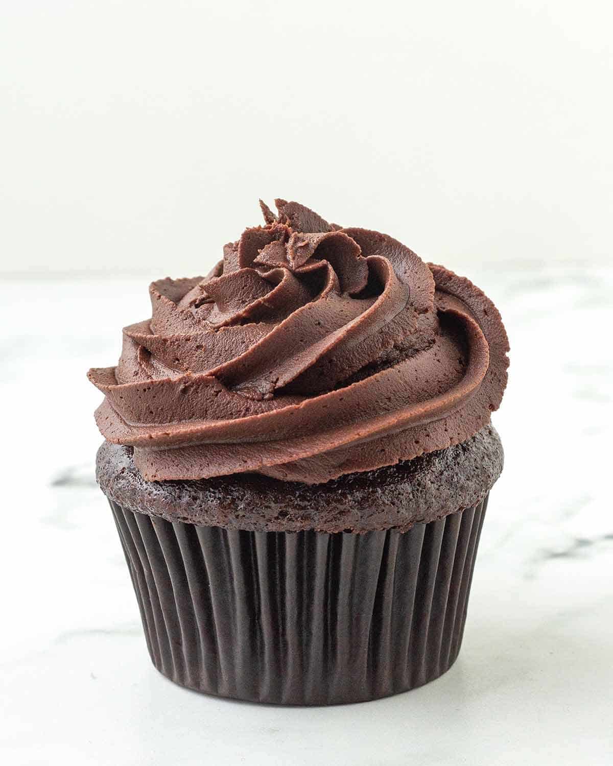 A chocolate cupcake topped with dairy-free chocolate ganache frosting.
