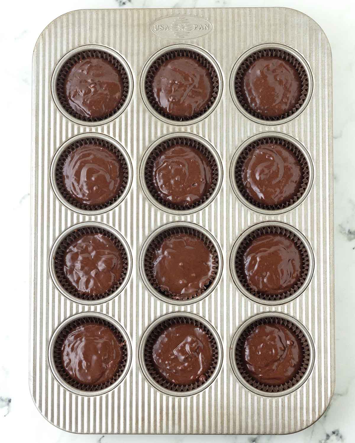 Unbaked chocolate cupcake batter in a cupcake pan.