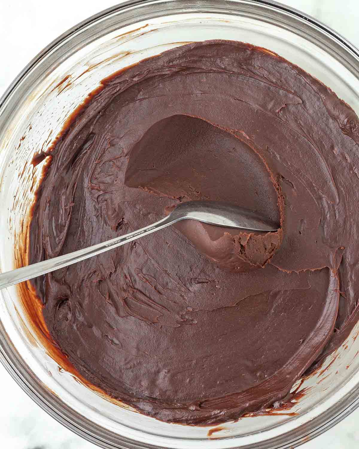 A spoon sliding through chilled chocolate ganache.