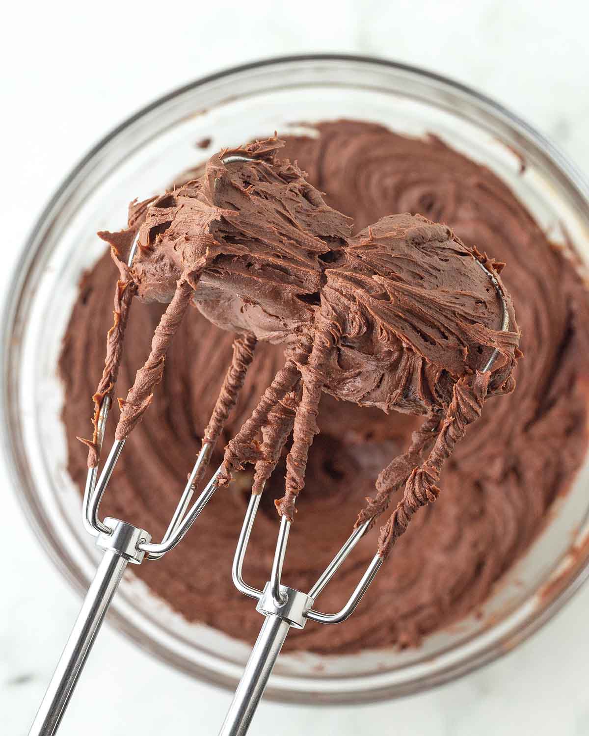 Chocolate ganache frosting on the beaters of an electric mixer.