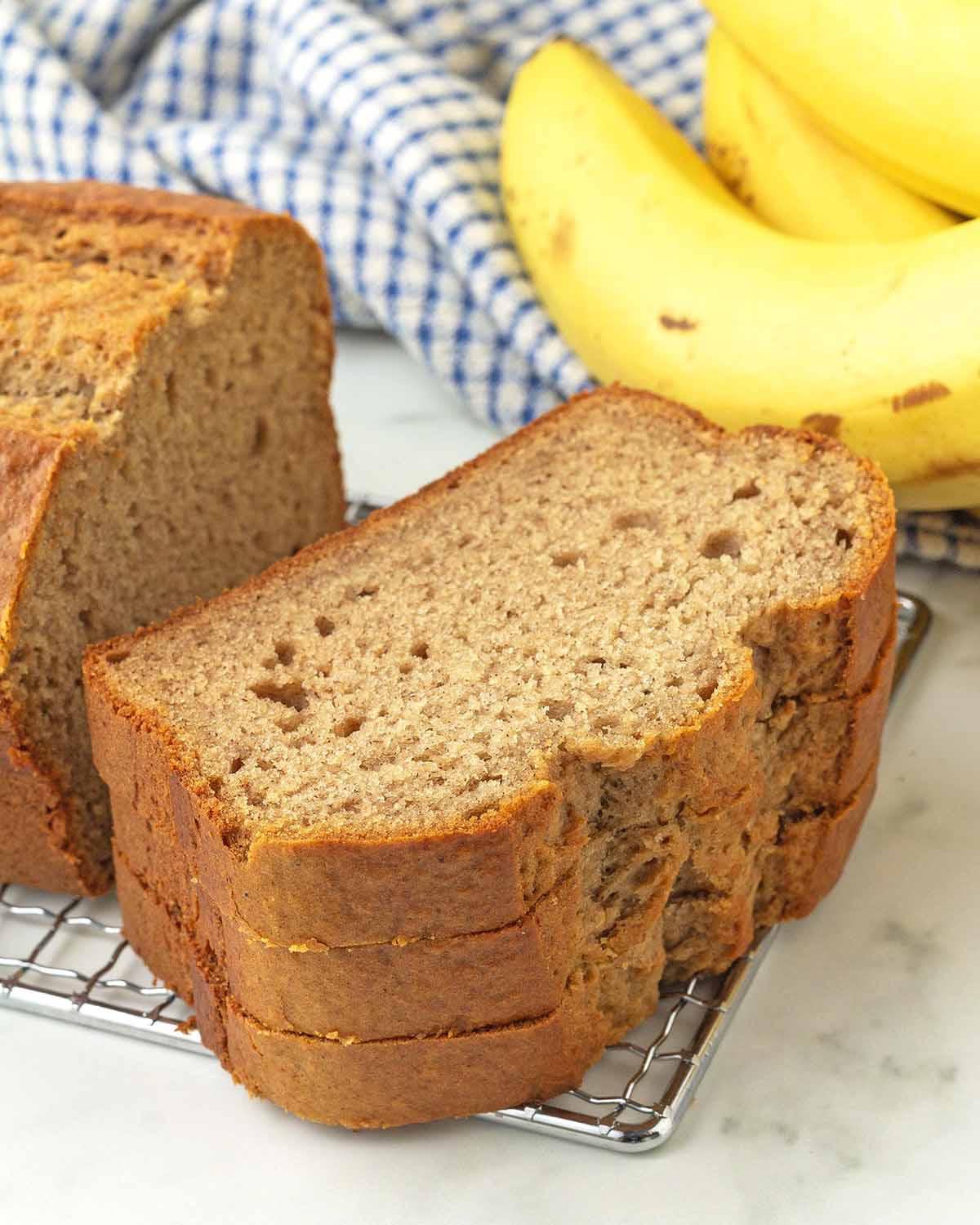 A stack of three slices of banana bread on a metal rack.