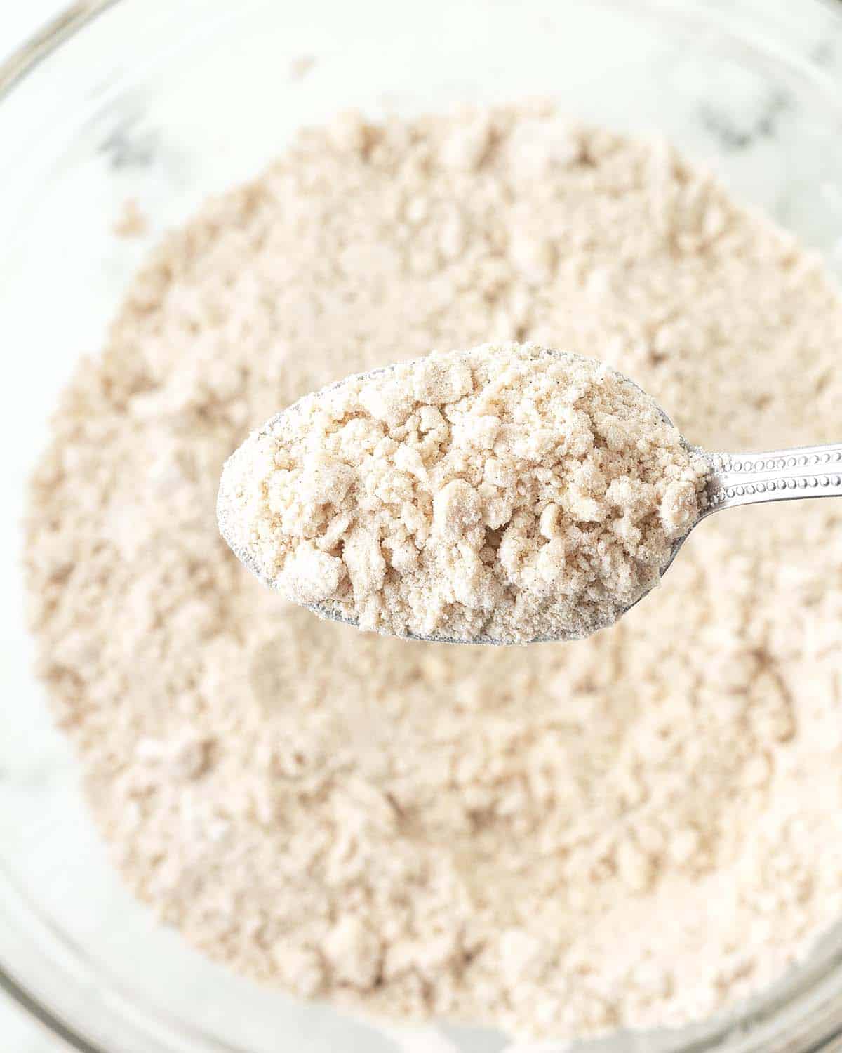A spoon full of dry ingredients that has had butter cut into it to make scones.