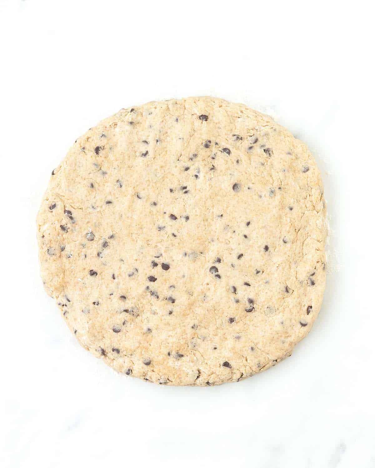 A circle of raw uncut chocolate chip scone dough.