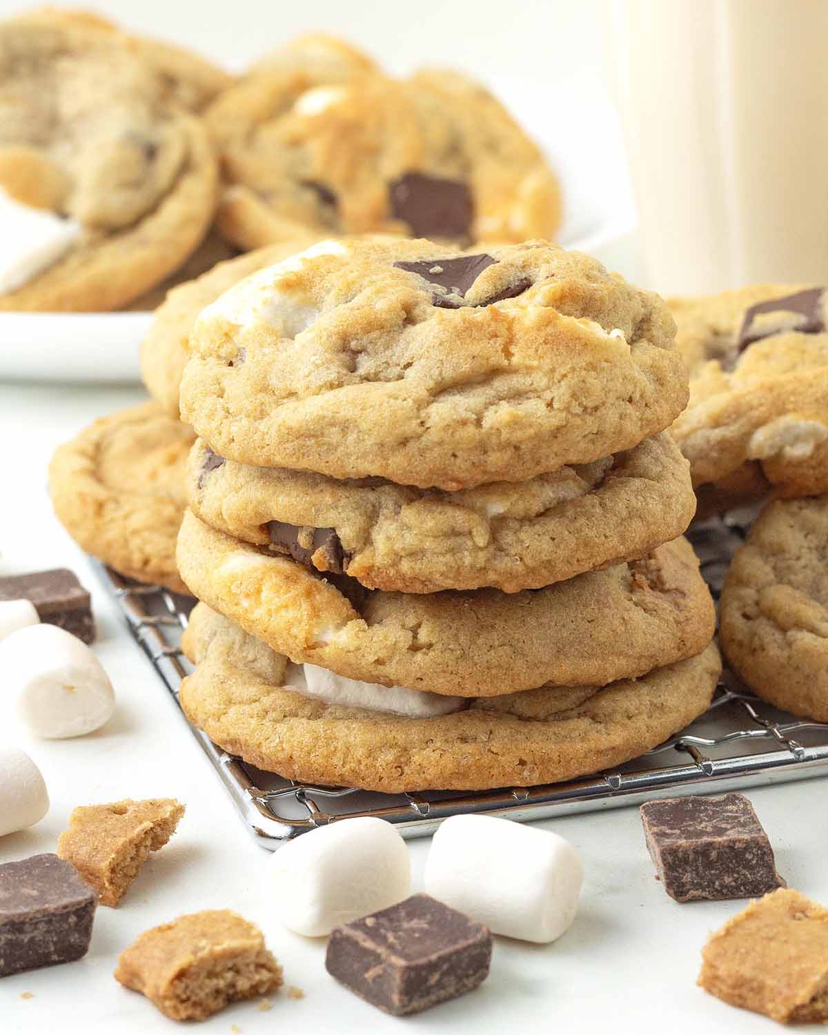 Four vegan s'mores cookies stacked on top of each other, the stack is sitting on a metal rack with other cookies behind it.