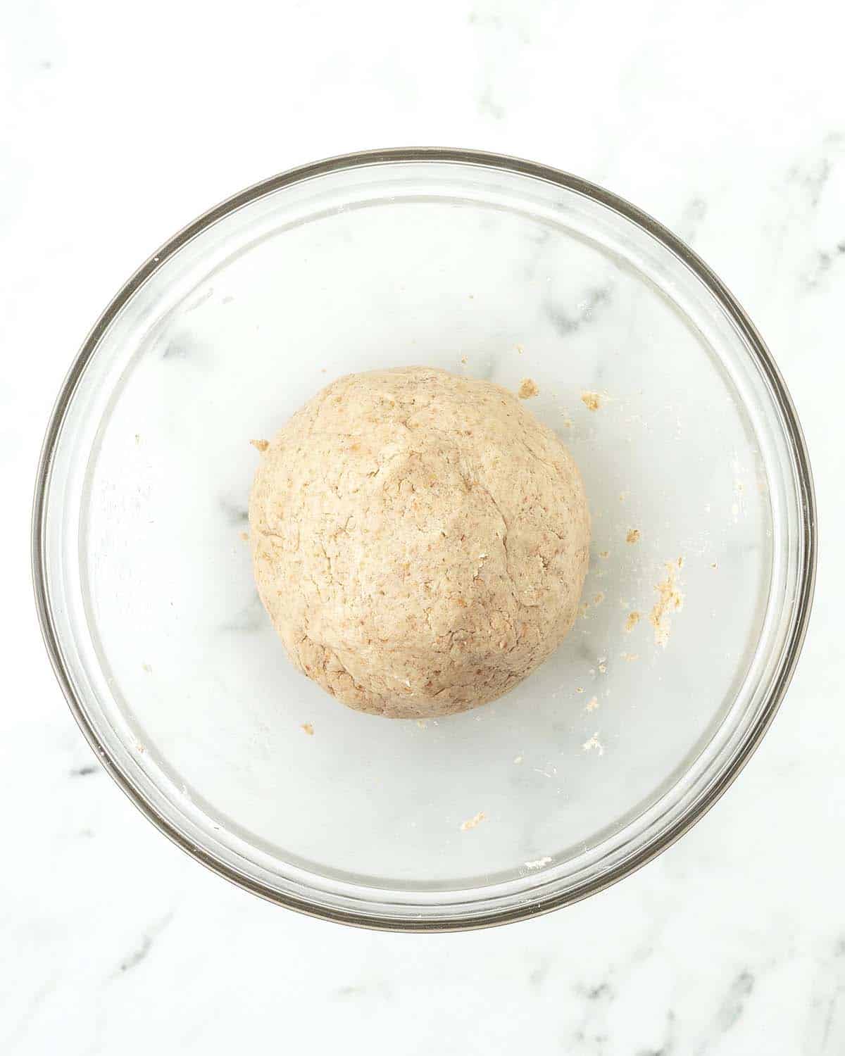 A ball of cookie dough in a glass bowl.