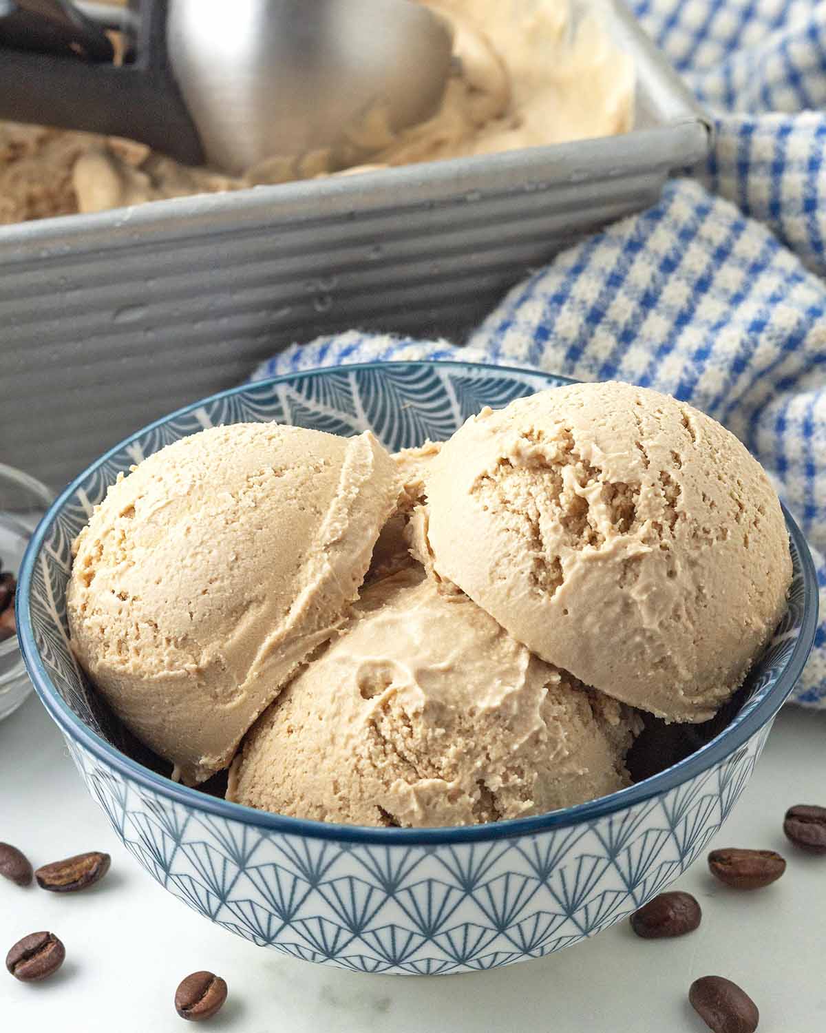 Three scoops of coffee ice cream in a blue bowl.