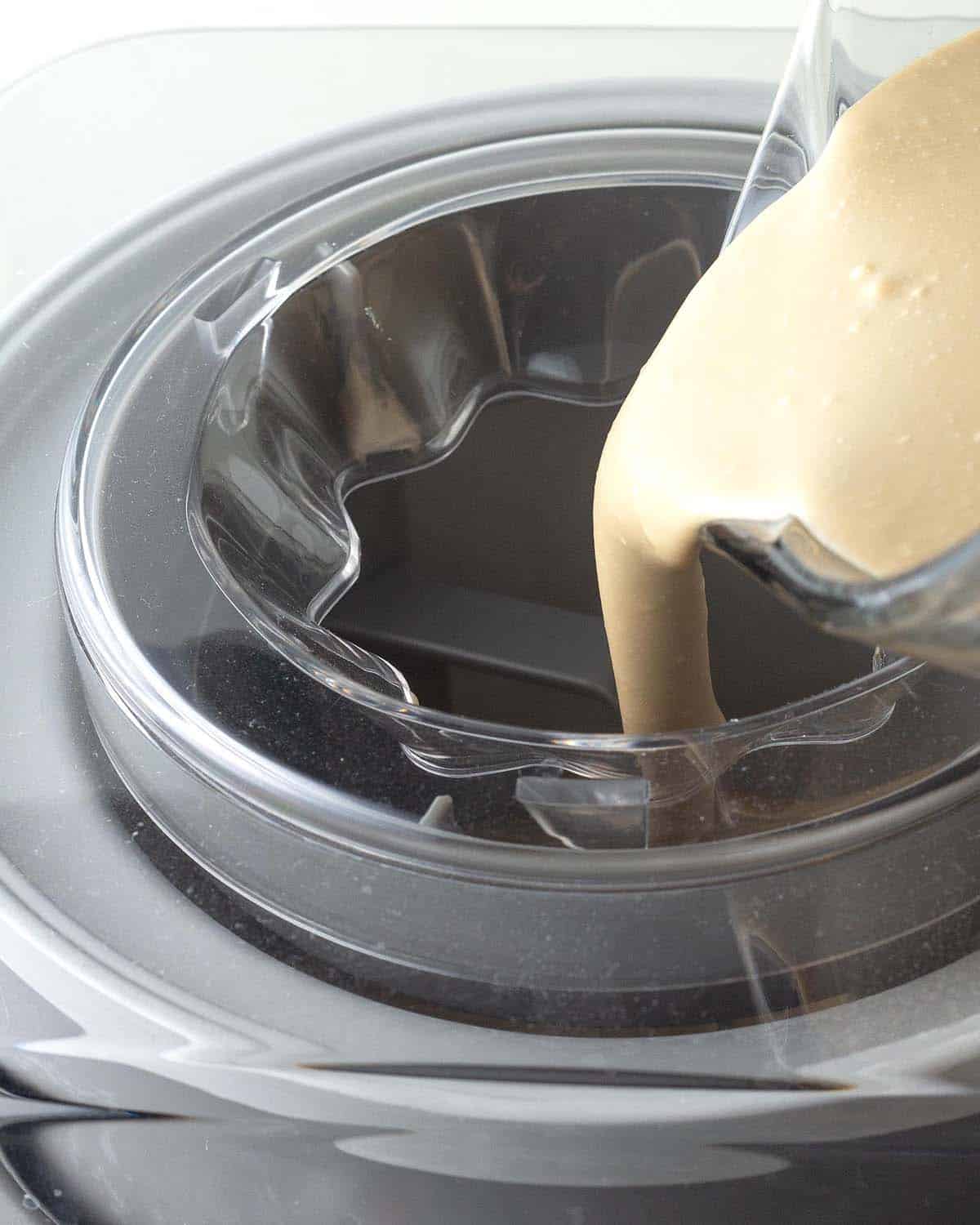 The base for coffee ice cream being poured into an ice cream maker.
