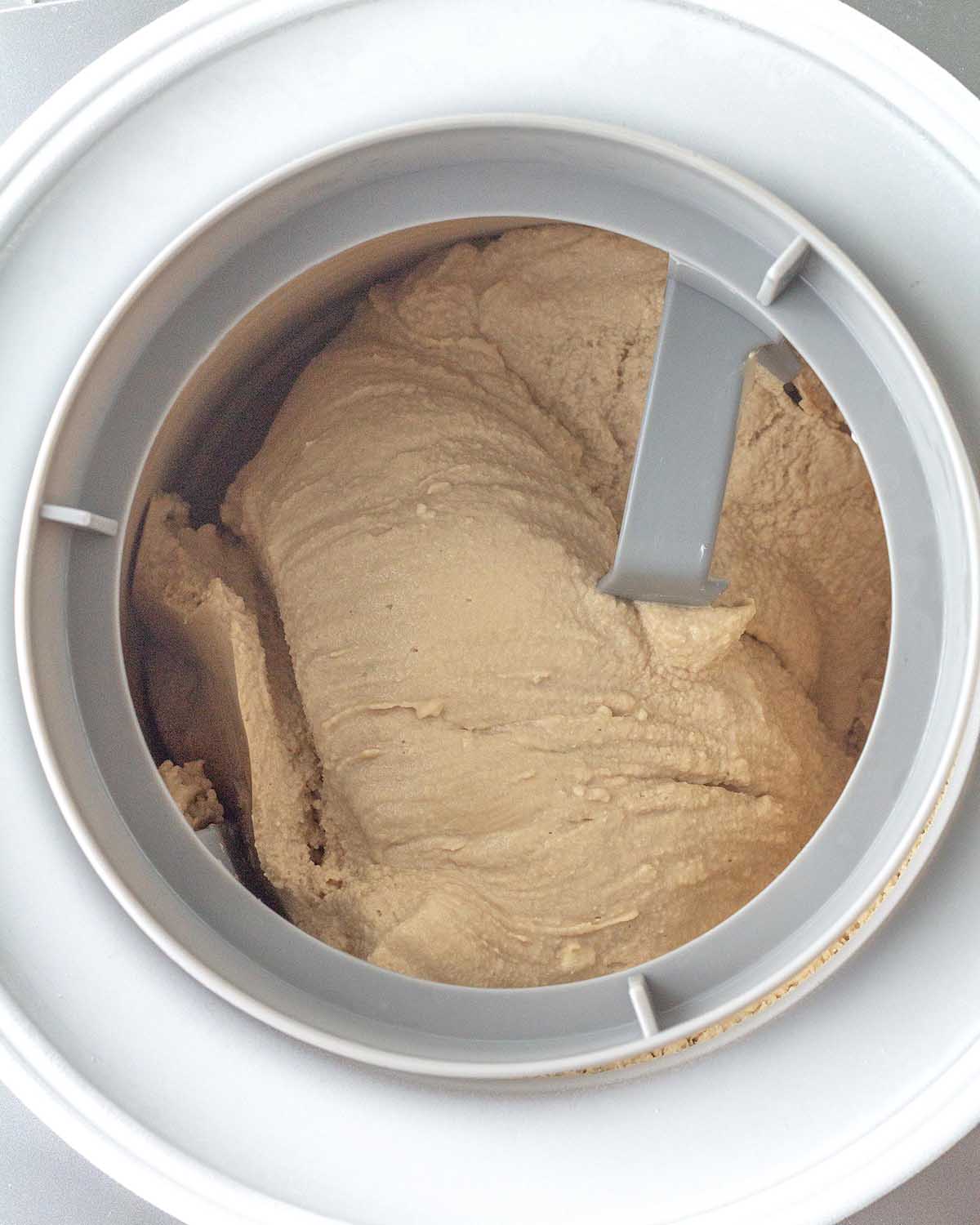 Vegan coffee ice cream being churned in an ice cream maker.