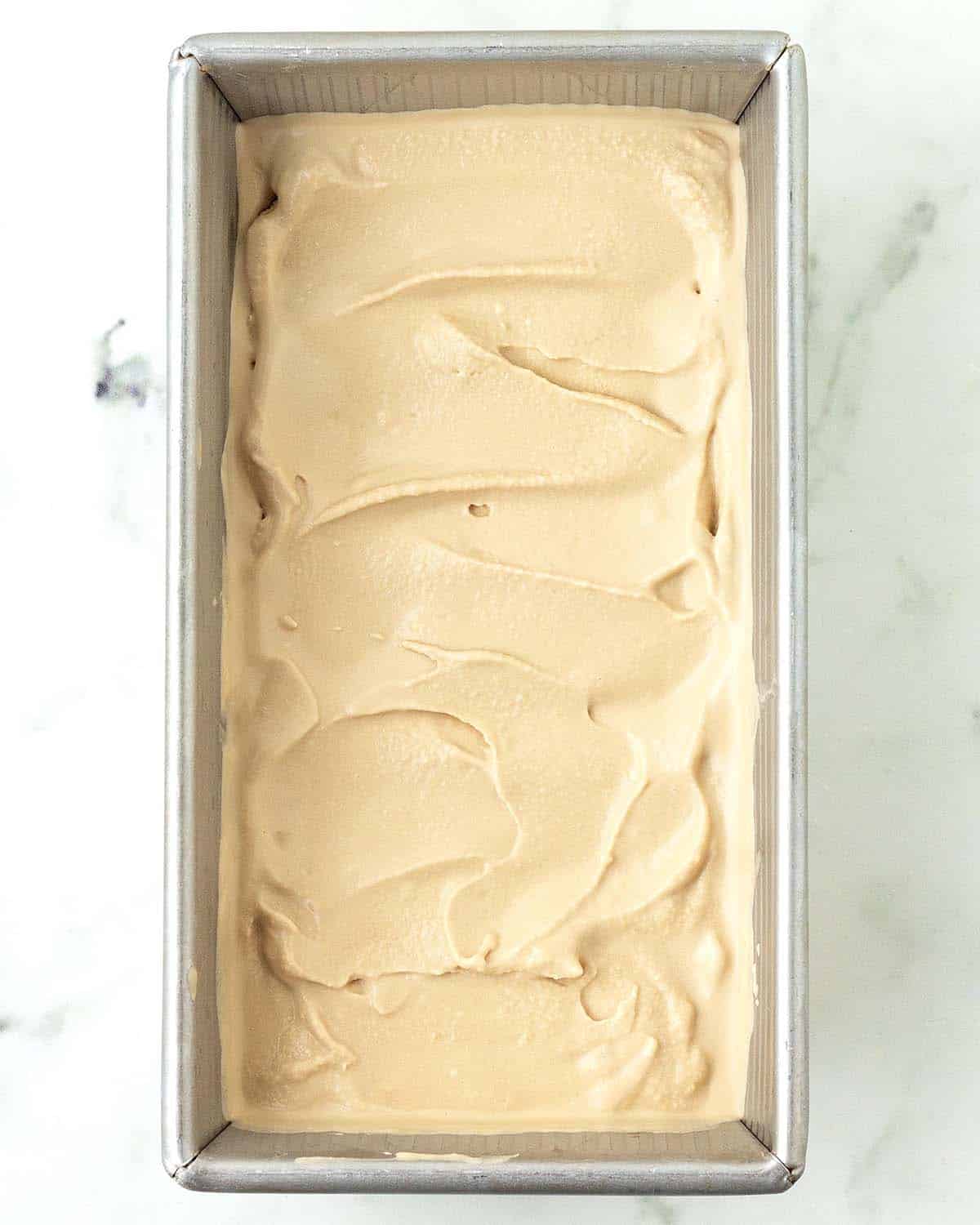 Soft serve vegan coffee ice cream in a metal pan.